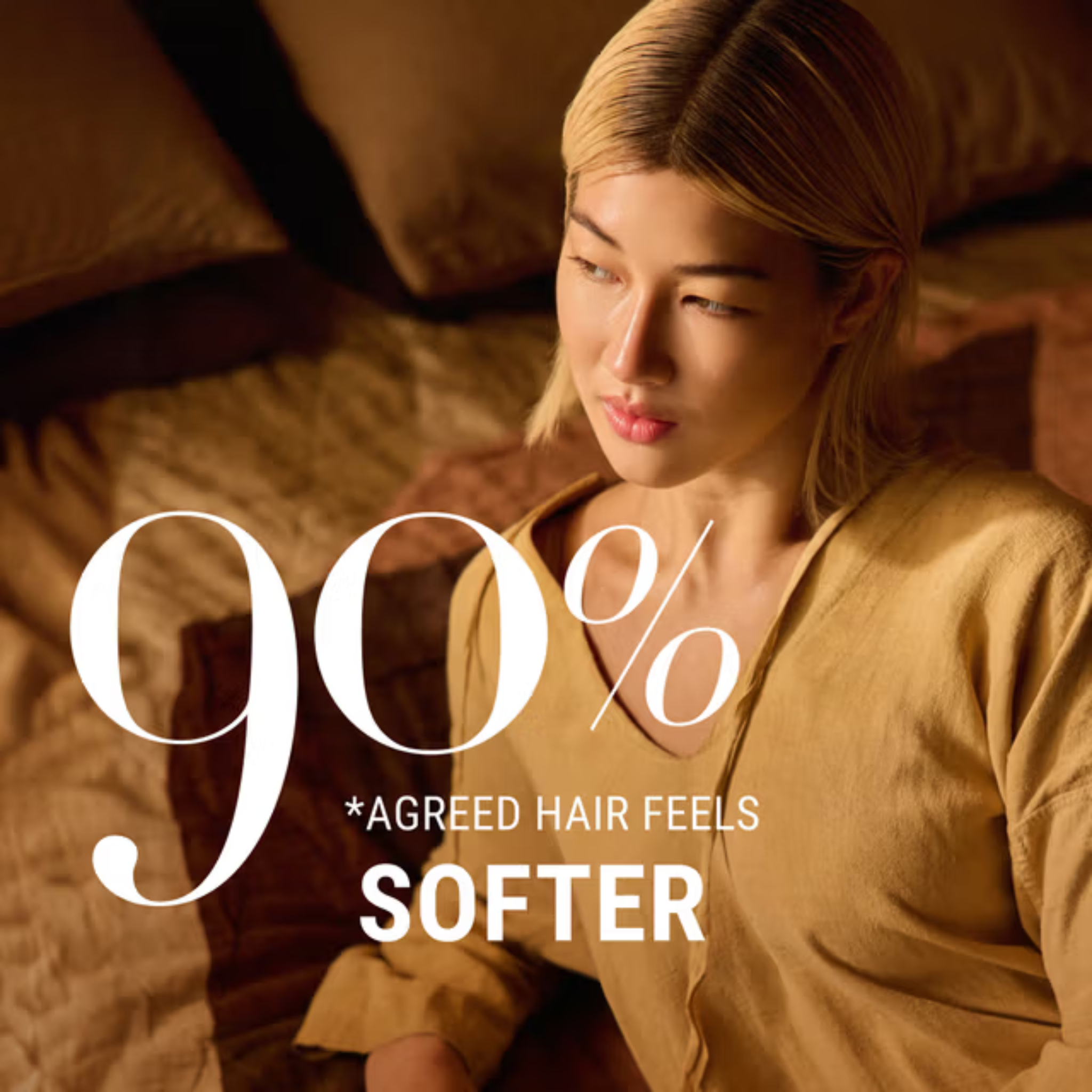 Woman sitting on a bed with text overlay about hair softness using Antipodes Peach Freesia Shampoo.