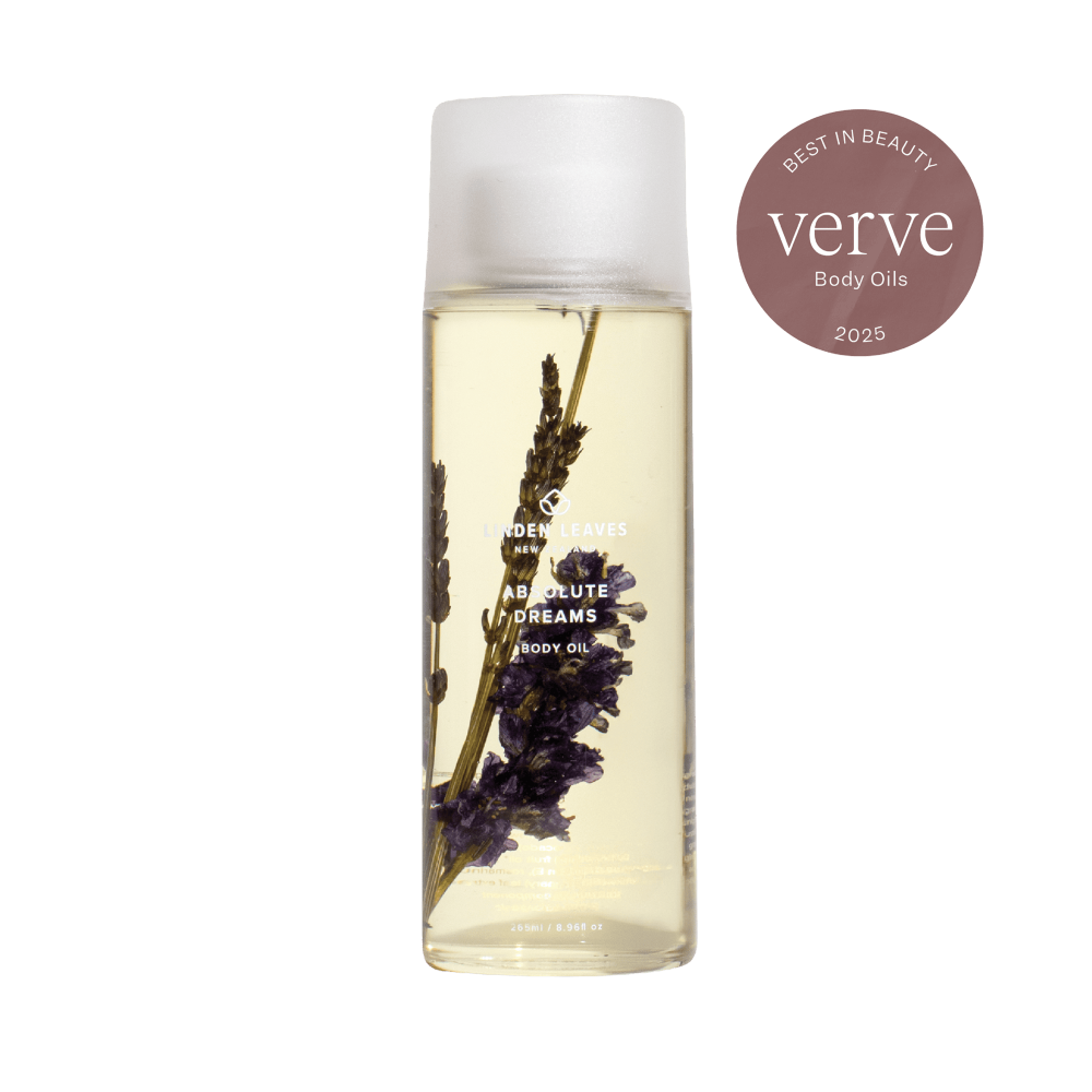 Bottle of Linden Leaves Absolute Dreams body oil with lavender flowers on a white background, featuring the Verve Beauty award.