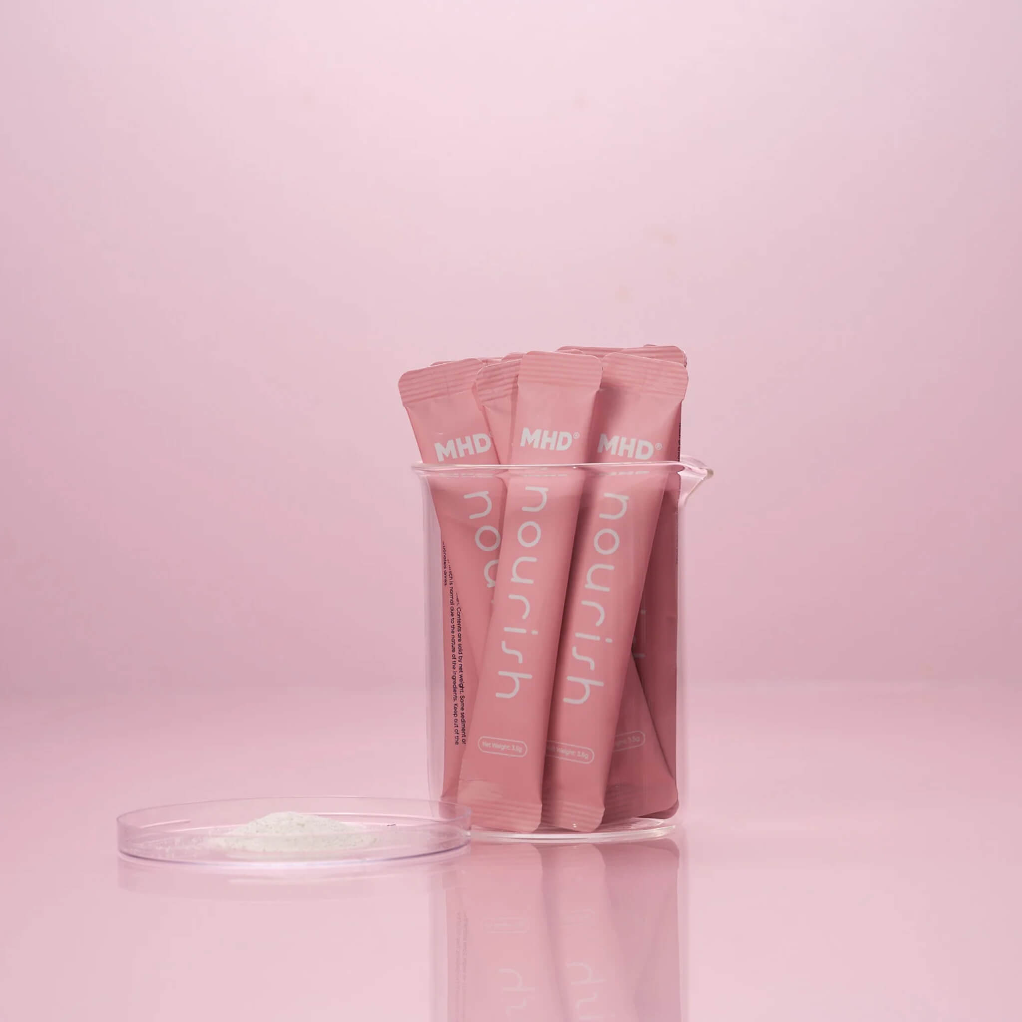 Pink MHD Hair & Skin Collagen and Bamboo Sachets labeled 'nourish' in a beaker on a pink background
