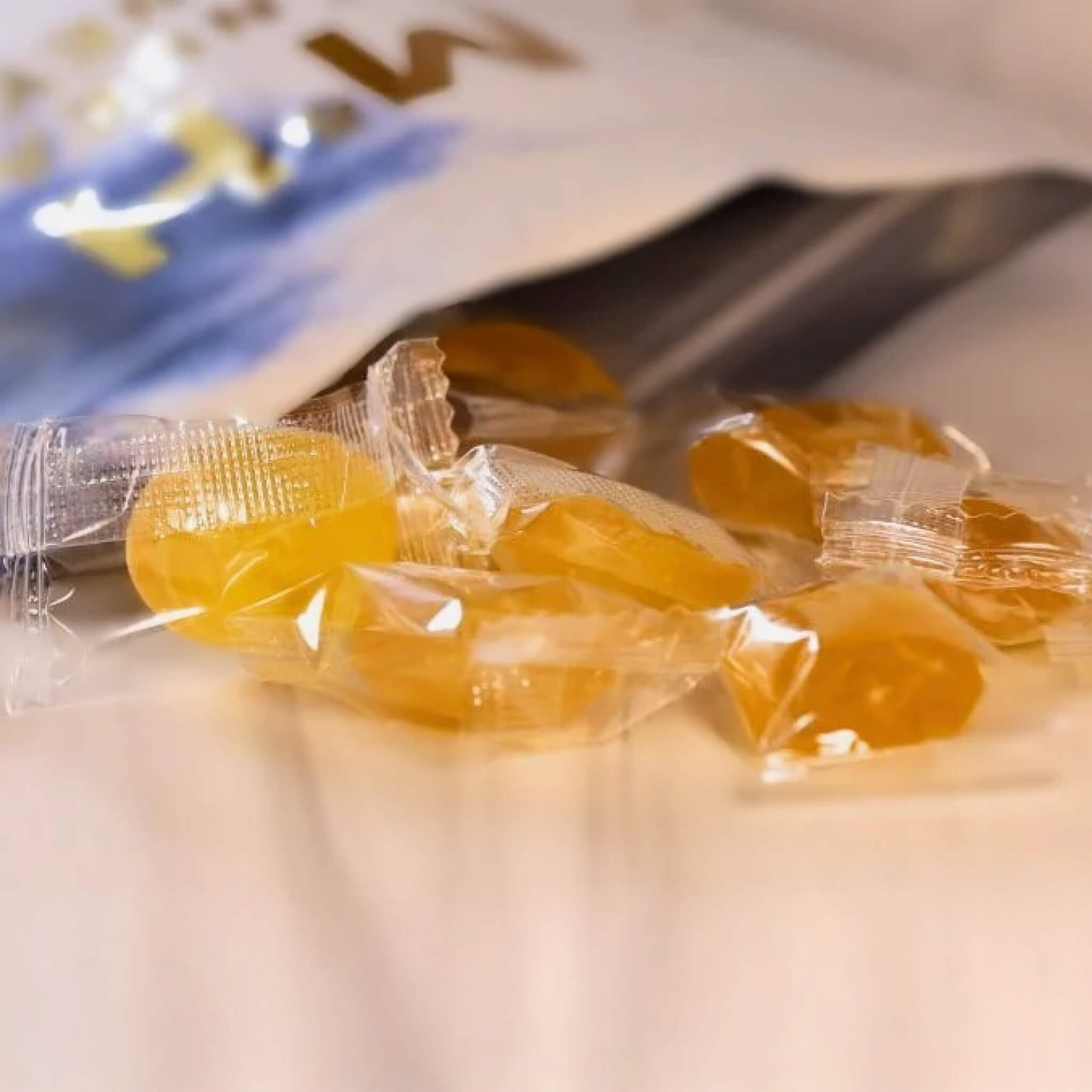 Small round candies in clear wrappers on a white surface with a blurred background
