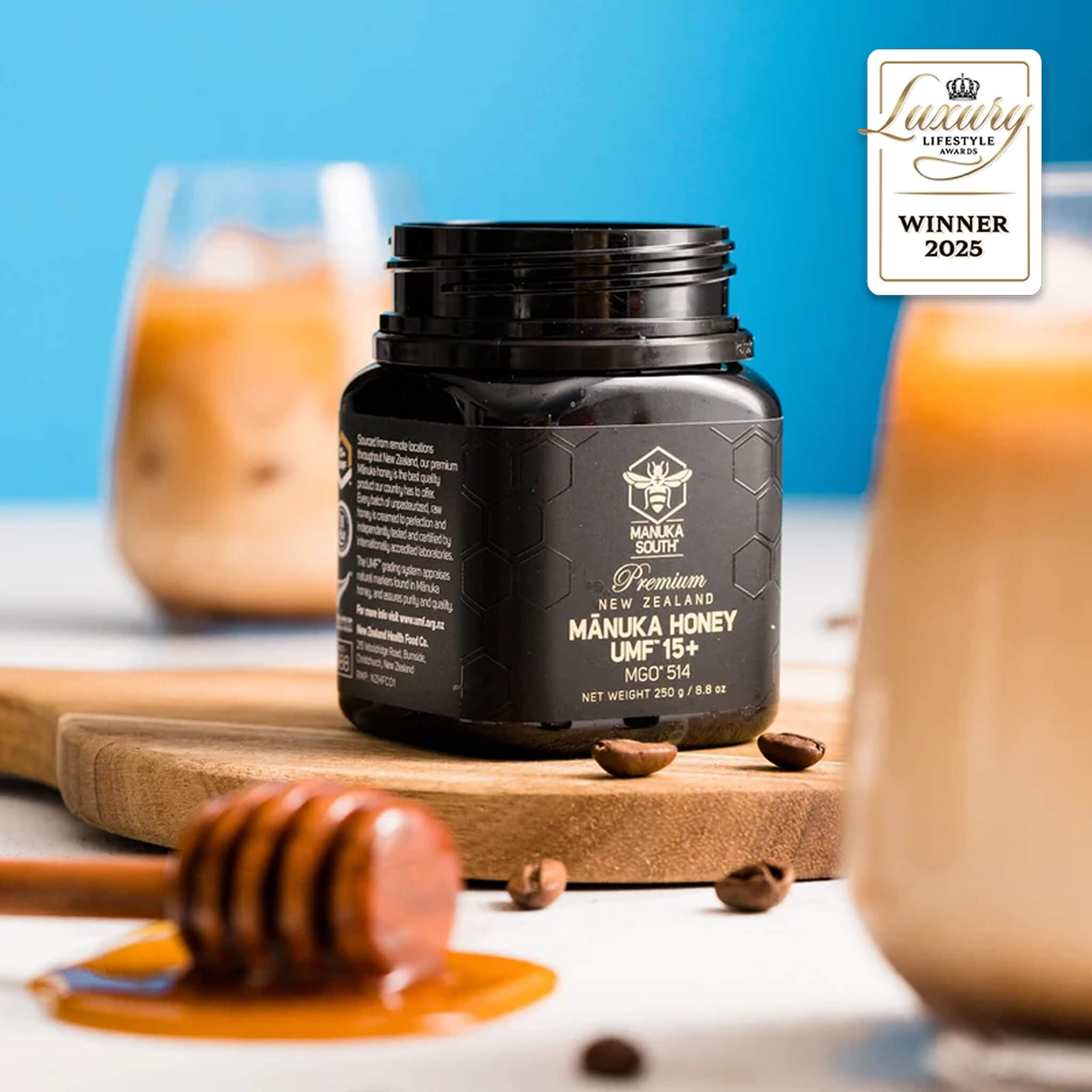 Manuka South Manuka Honey UMF 15+ 250g jar with honey dipper and coffee on a wooden board, featuring a 'Lifestyle Winner 2025' badge.