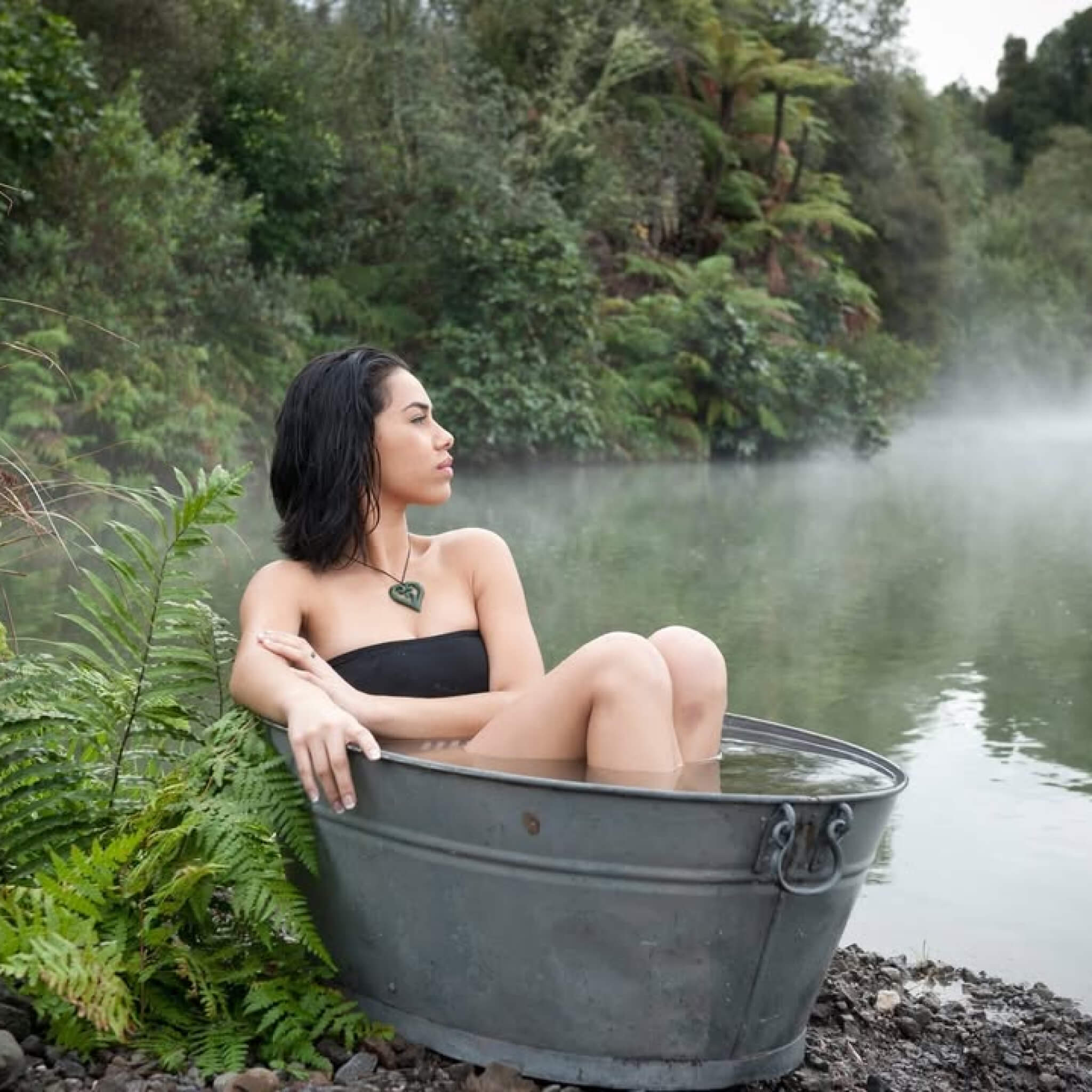 Woman sitting in a metal bathtub by a Rotorua thermal springs