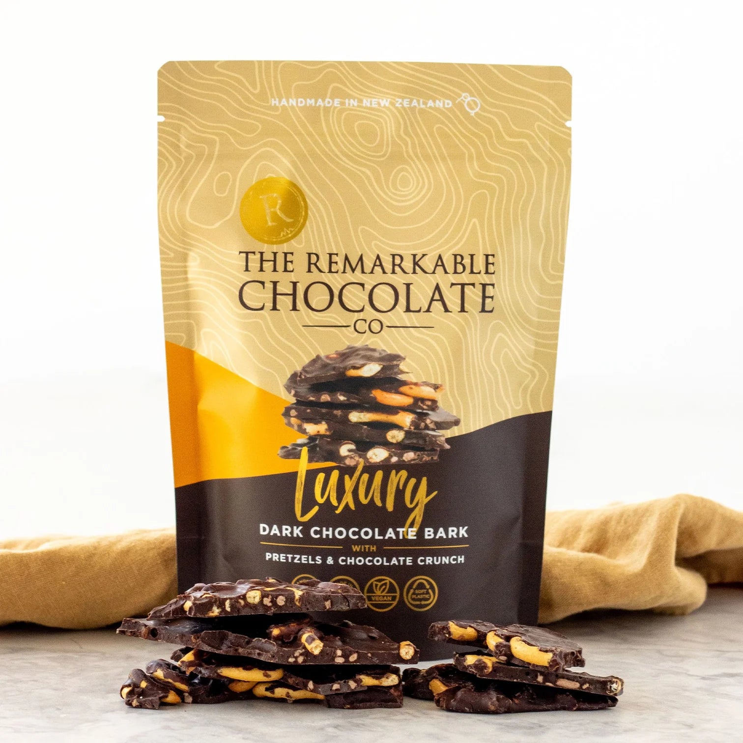 Packaging of The Remarkable Chocolate Co. Luxury Dark Chocolate Bark with pretzels and chocolate crunch on a white background.