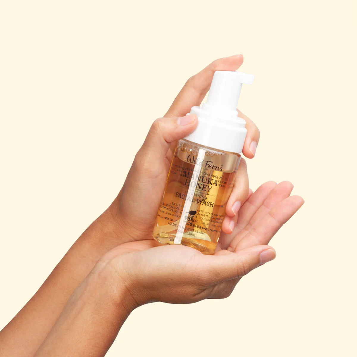 Hand holding a bottle of Wild Fenns Manuka Honey Face wash against a beige background