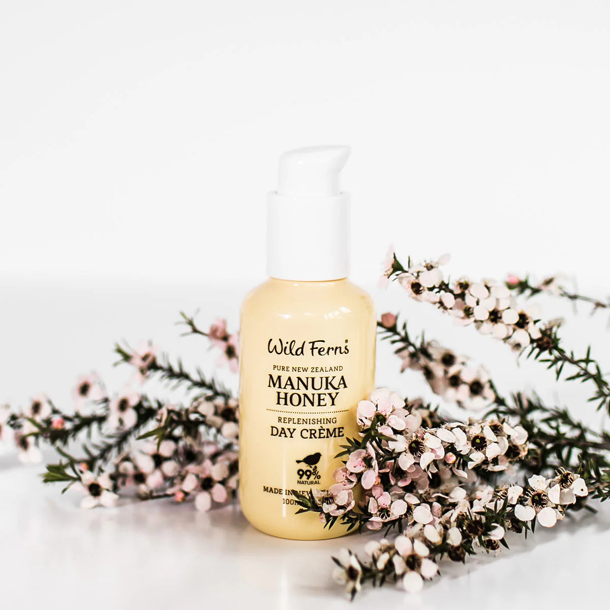 Wild Ferns Manuka Honey Day Creme bottle with floral arrangement on a white background