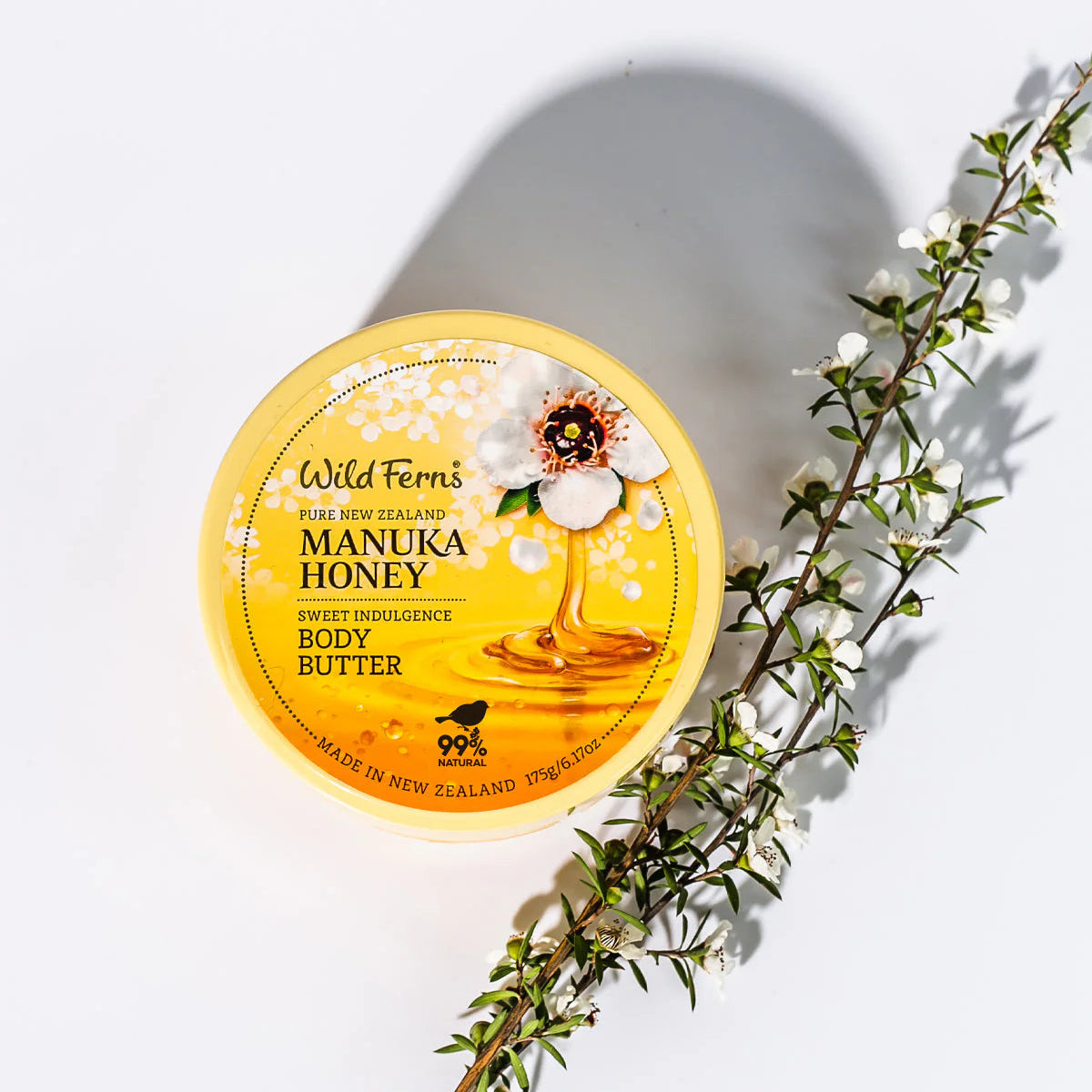 Wild Ferns Manuka Honey body butter with a branch on a white background