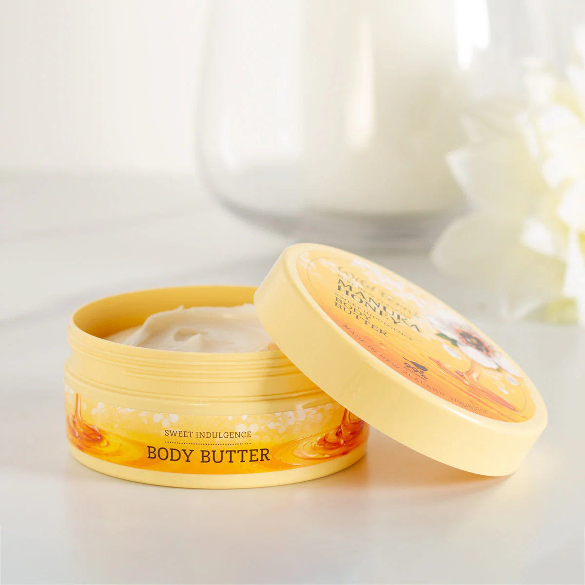 A container of Wild fern's body butter with a blurred candle in the background