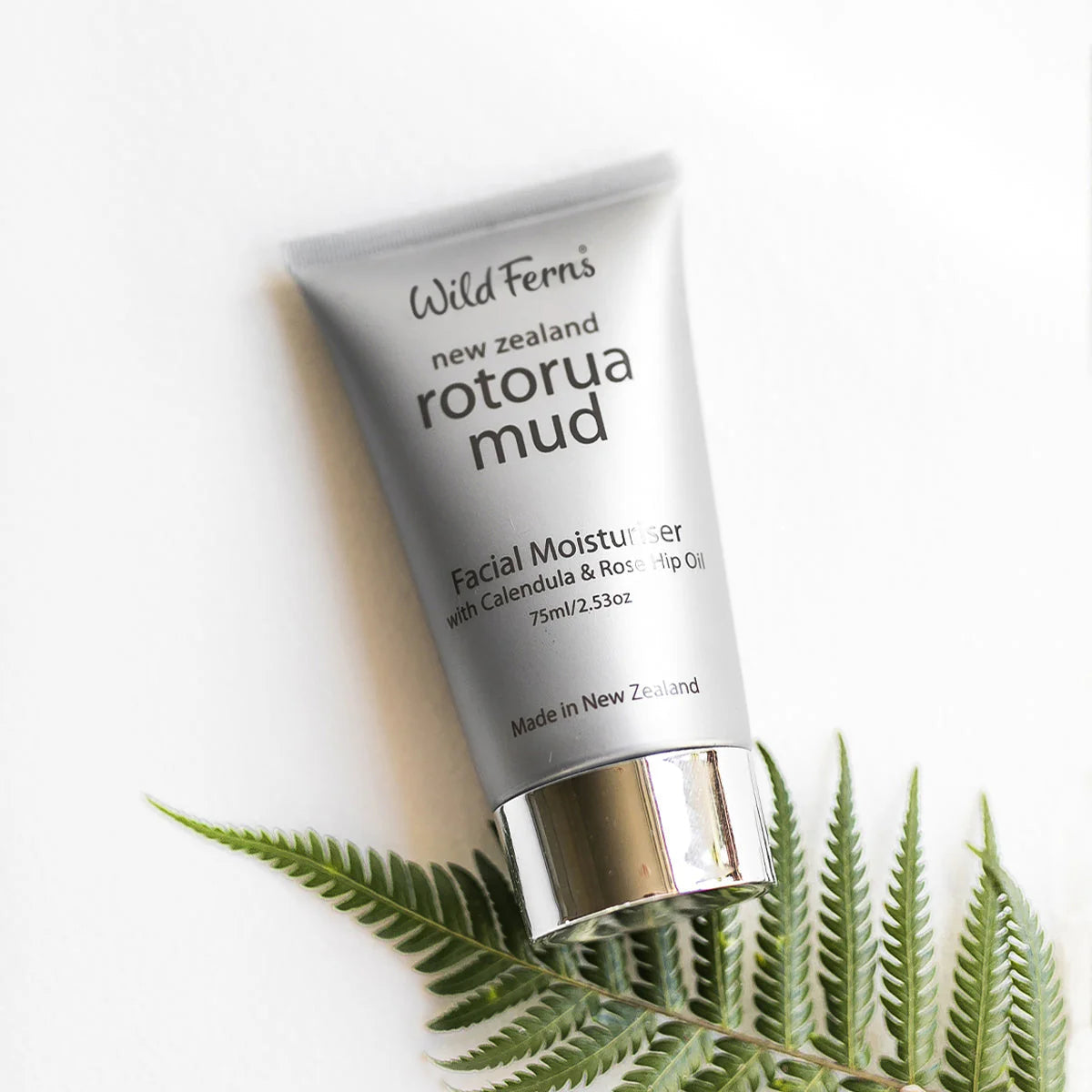 Tube of Wild Ferns Rotorua Mud facial moisturizer with a fern leaf on a white background