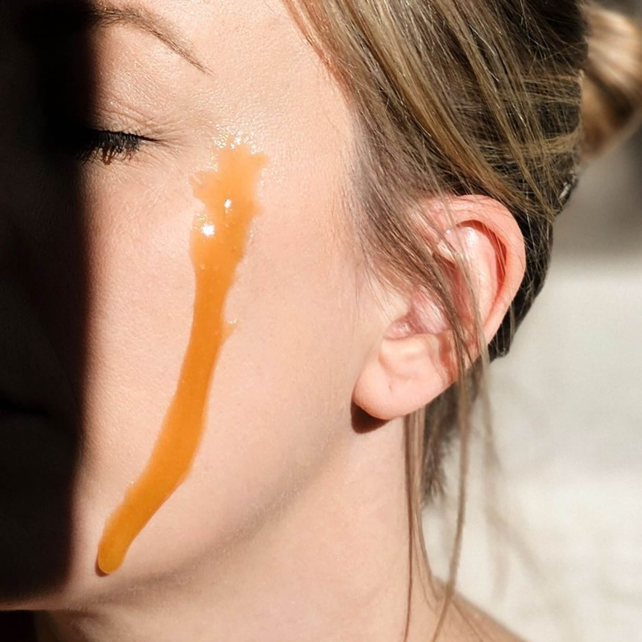 Close-up of a person's face with a streak of Steens Manuka Honey on their cheek.