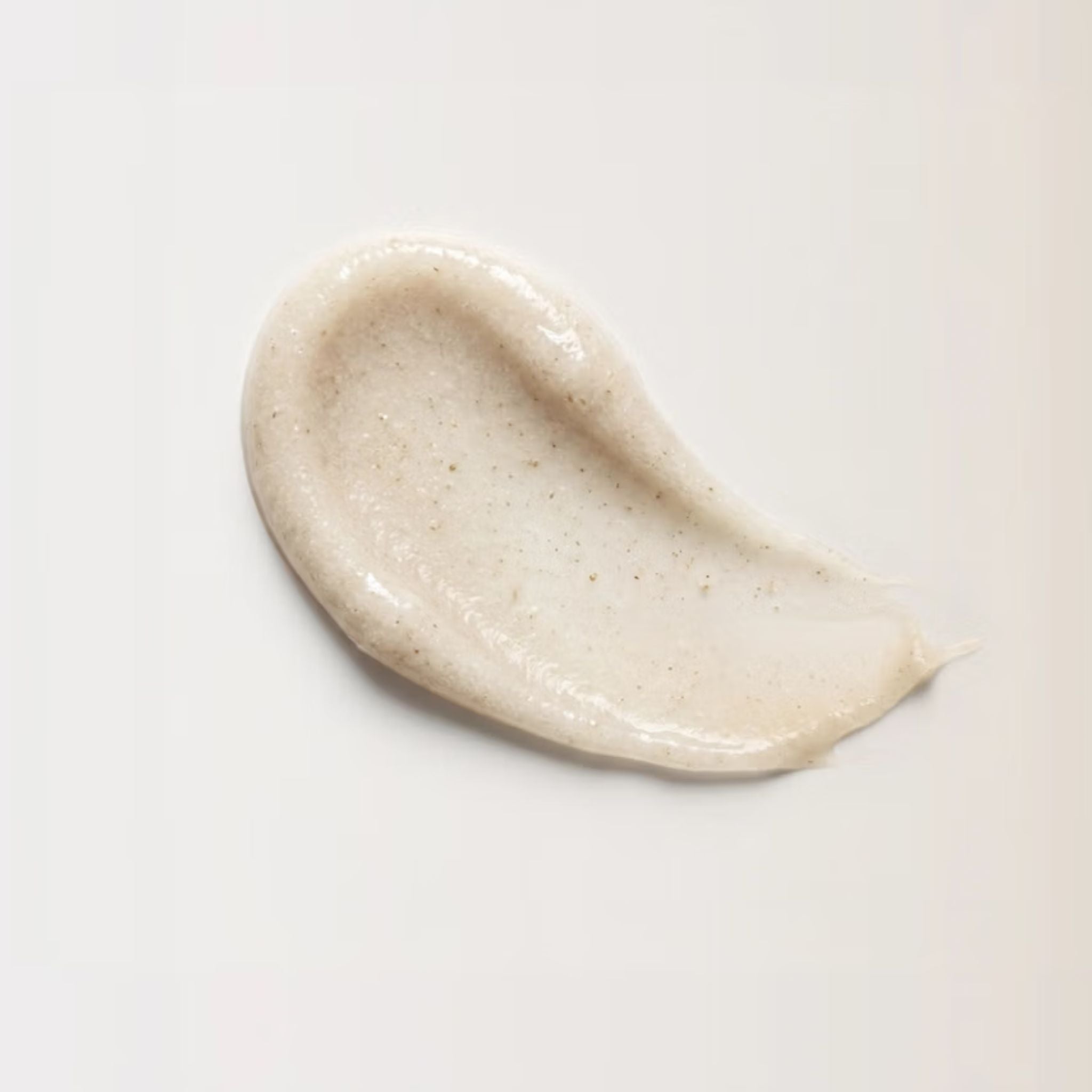 A thick, textured smear of a light beige cosmetic cream or gel with fine specks, shown on a clean white background.