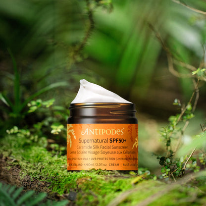 A jar of Antipodes Supernatural SPF50+ Sunscreen cream placed in a natural setting with moss and greenery in the background.