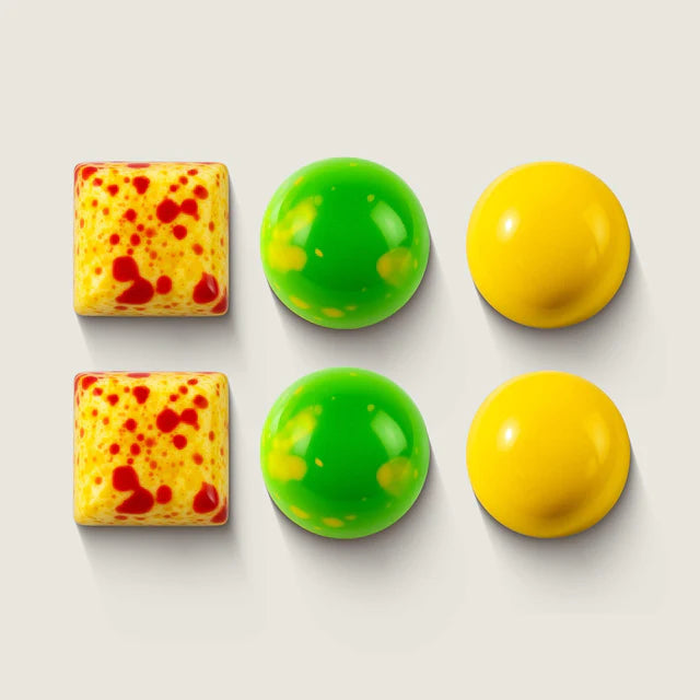 Six colorful chocolate bon bons in green, yellow, and red on a light gray background