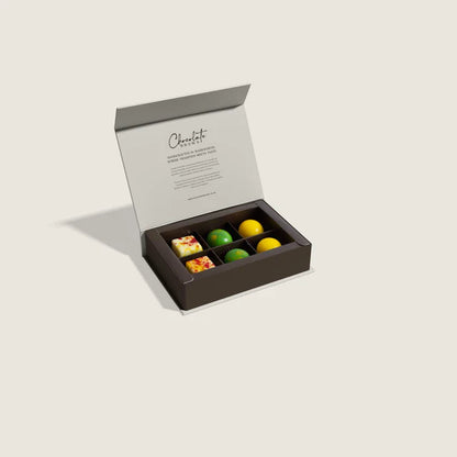 Open box of assorted tropical fruit chocolates on a light gray background