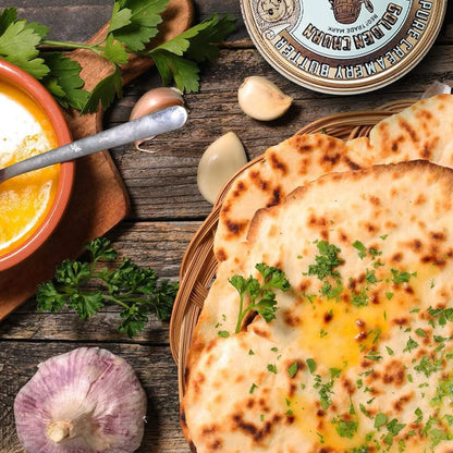 Flatbread with herbs on a wooden table with a tin of Golden Churn Butter