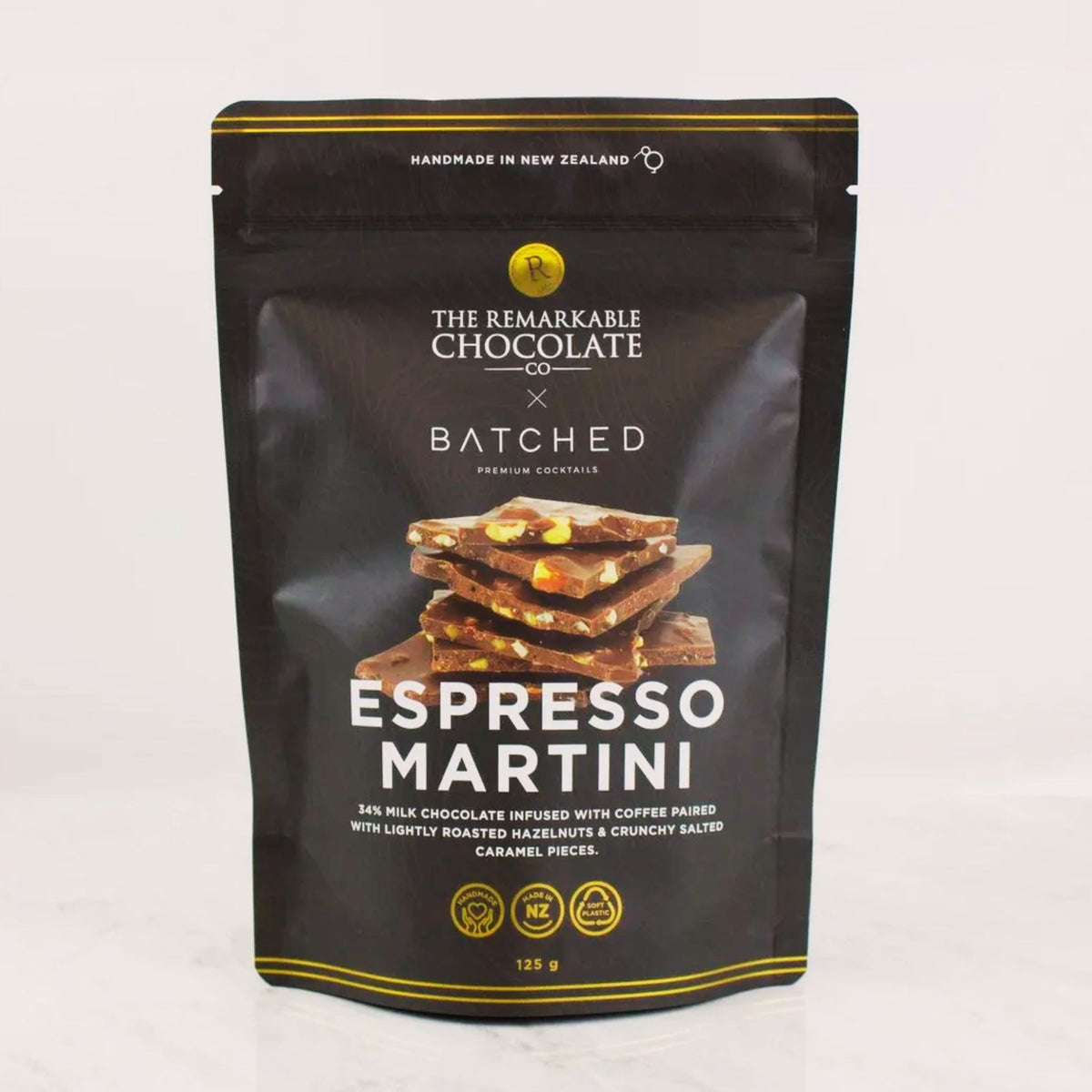 A 125g stand-up pouch of The Remarkable Chocolate x Batched Espresso Martini chocolate bar, featuring a black background with gold accents and a photo of chocolate pieces on the front.