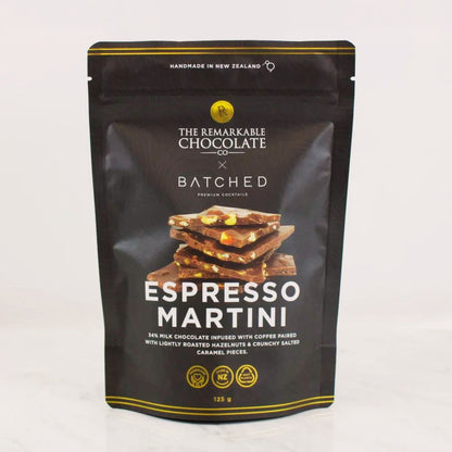 A 125g stand-up pouch of The Remarkable Chocolate x Batched Espresso Martini chocolate bar, featuring a black background with gold accents and a photo of chocolate pieces on the front.