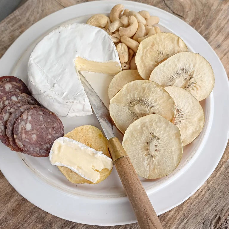 Assorted cheese, crackers, and little beauties dried kiwifruits on a white plate with a knife.