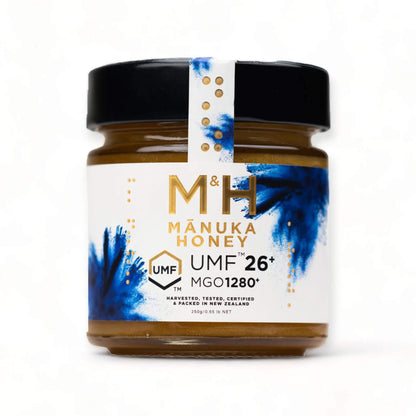 M&H Manuka Honey UMF 26+ jar with blue and white label on a white background