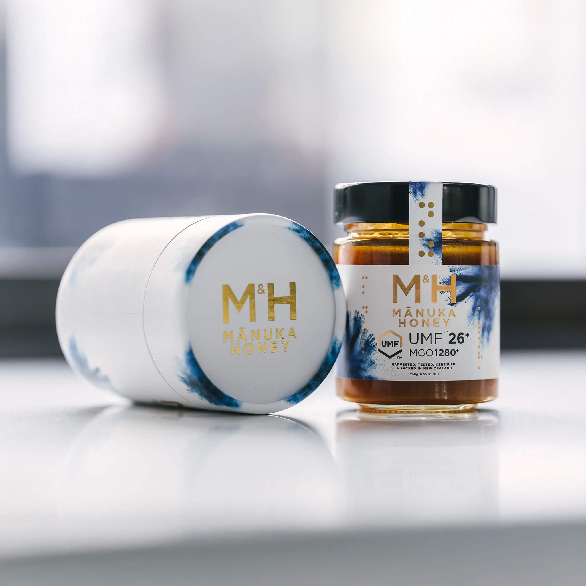 M&H Manuka Honey UMF 26+ jars with Mánuka Honey branding on a light background