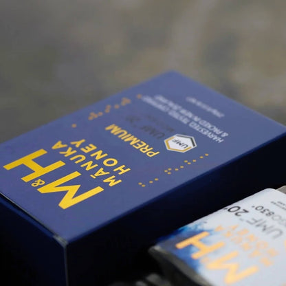 Blue M&H Manuka Honey UMF 20+ packaging with yellow text on a blurred background