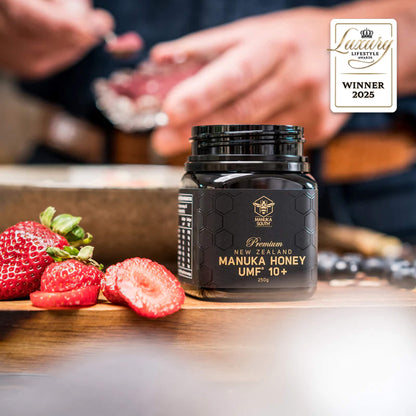 Manuka South Manuka honey UMF10+ 250g jar with strawberries on a wooden surface, featuring a 'Winner 2025' badge.
