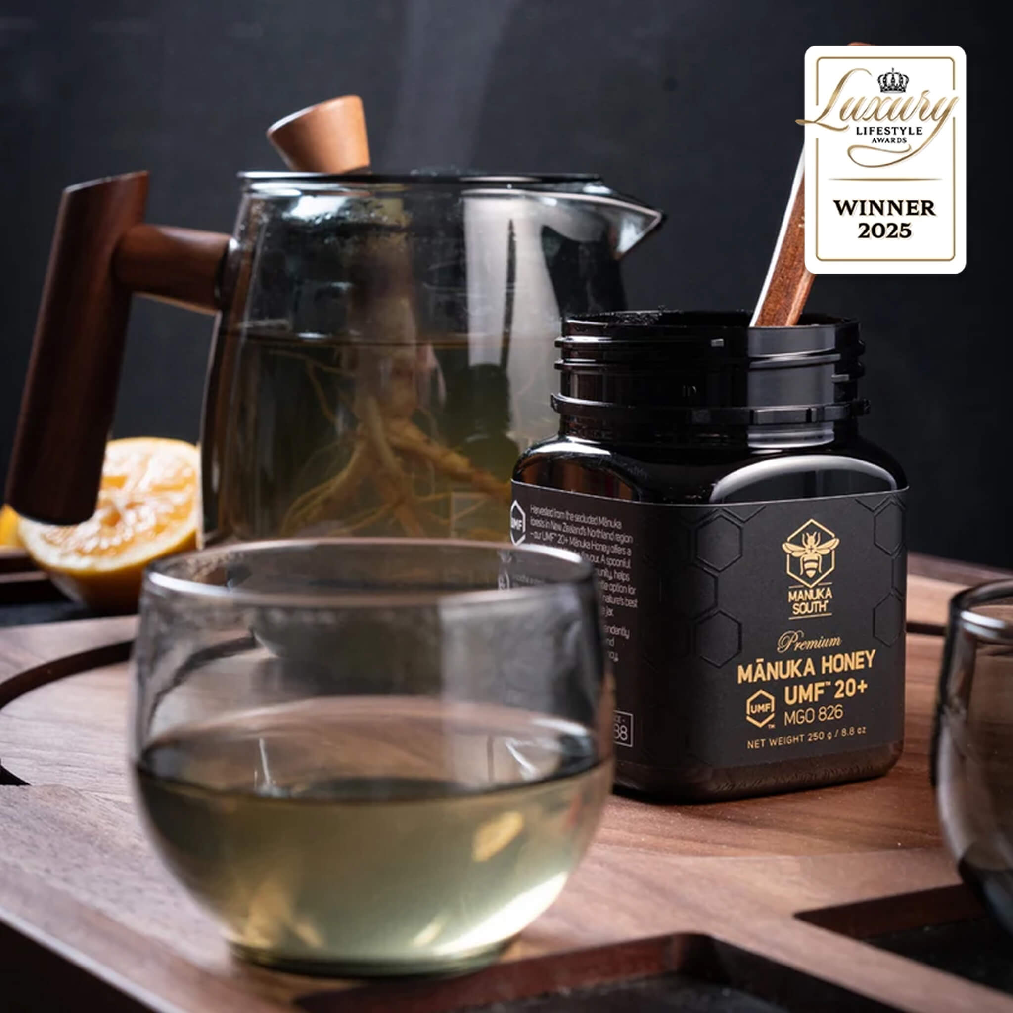 Manuka South Manuka honey UMF 20+ 250g jar with a glass of tea on a wooden tray, featuring a 'Luxury Lifestyle Award' winner badge.