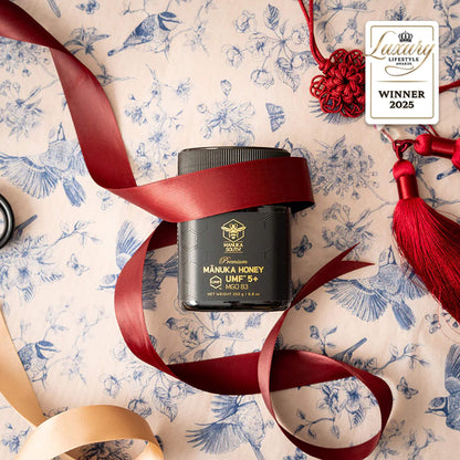 Manuka South Manuka Honey UMF5+ 250g container with red ribbon on a patterned background, featuring a 'Luxury Lifestyle' award badge.