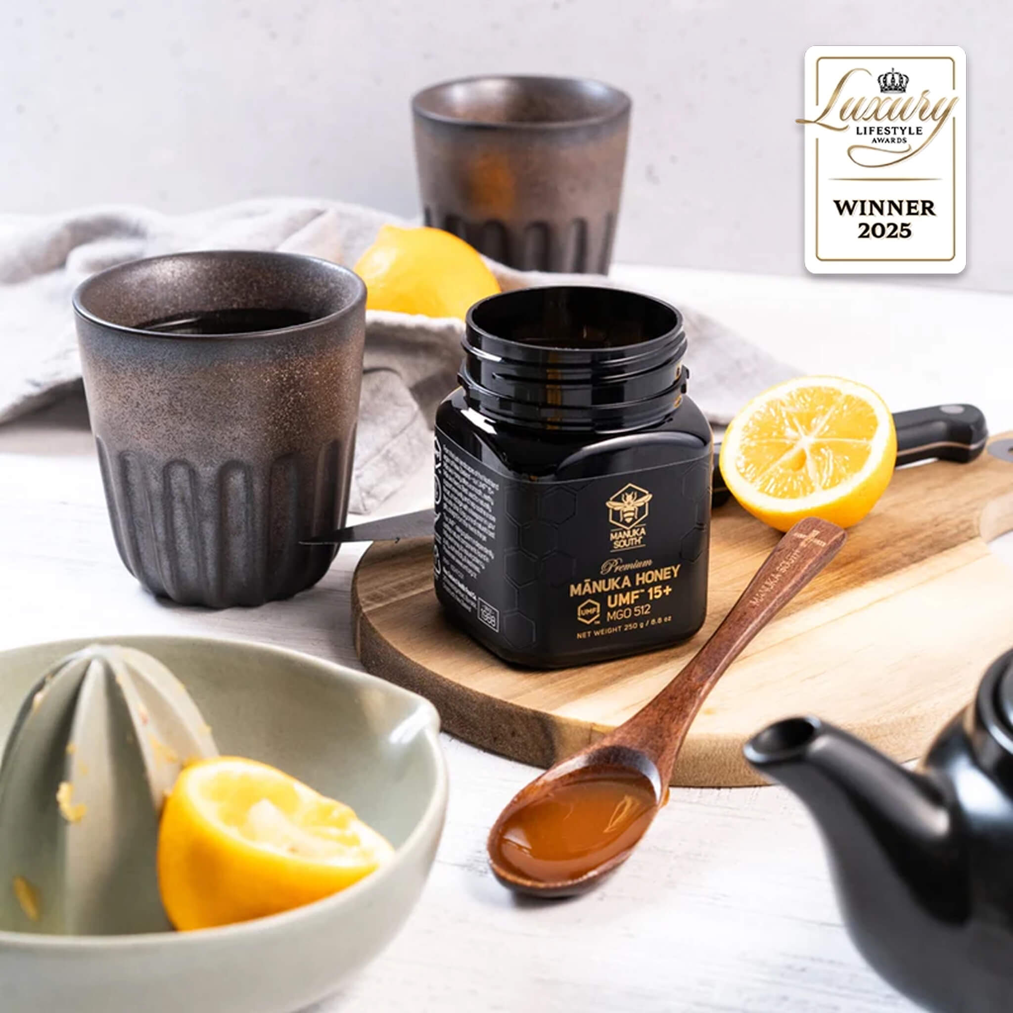 Manuka South Manuka Honey UMF 15+ 250g jar with lemons and cups on a table, featuring a 'Lifestyle Award Winner' badge.