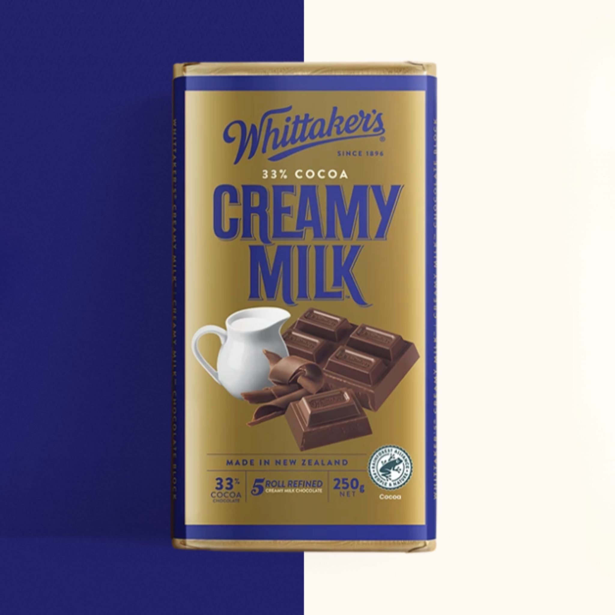 A single Whittaker's Creamy Milk chocolate bar in its packaging, shown against a split blue and off-white background.