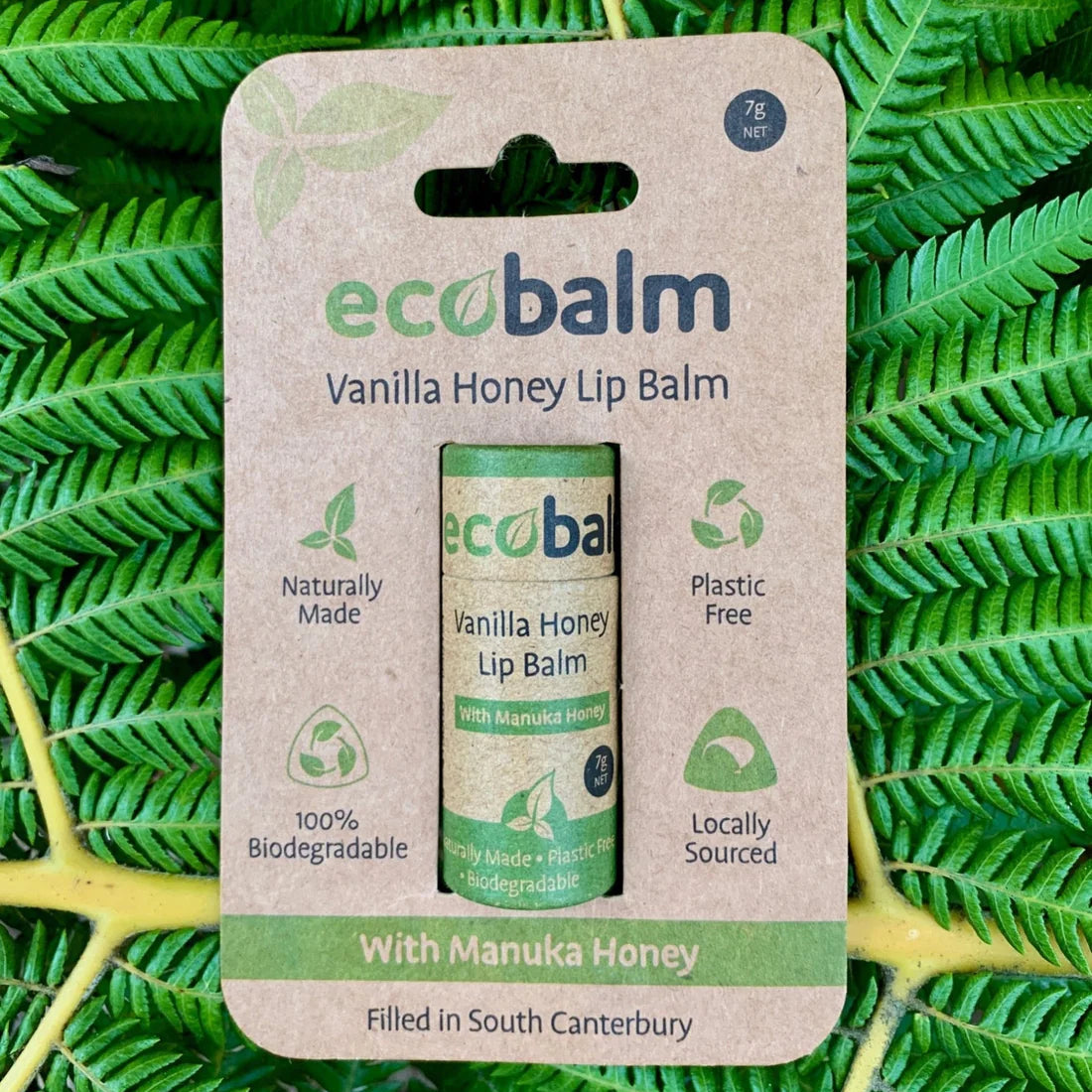 ecobase ecobalm Vanilla Honey Lip Balm packaging on a green leaf background