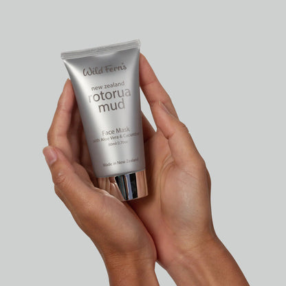 Hand holding a tube of Wild Ferns Rotorua Mud Face Mask against a plain background