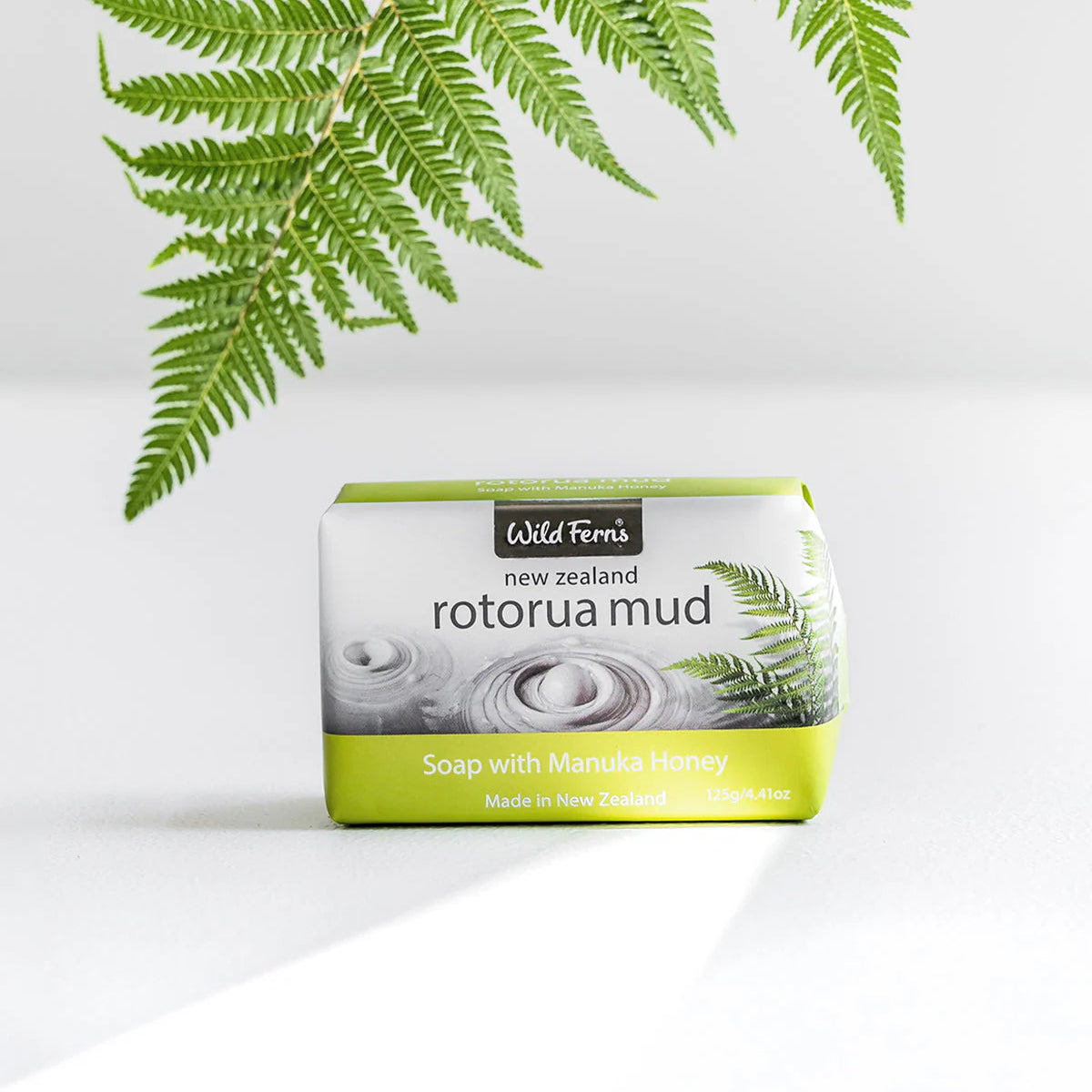 Soap bar with 'Rotorua Mud' packaging on a white background with green leaves.